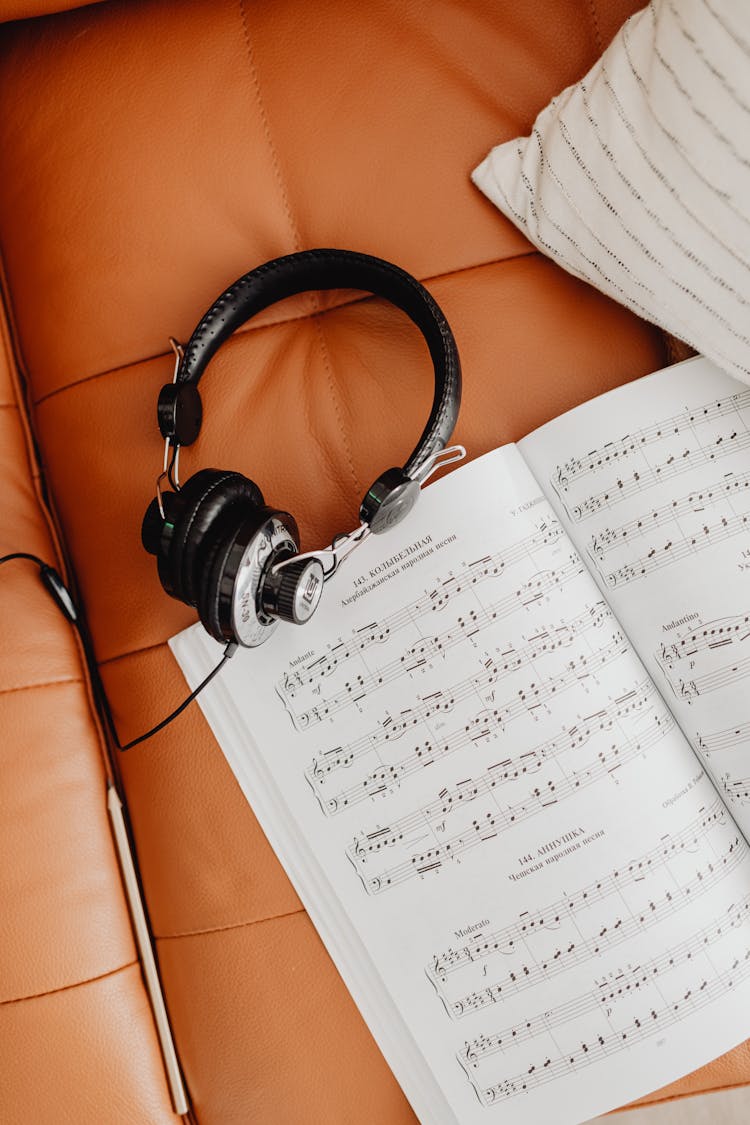 Headphones And A Music Sheet On A Couch 