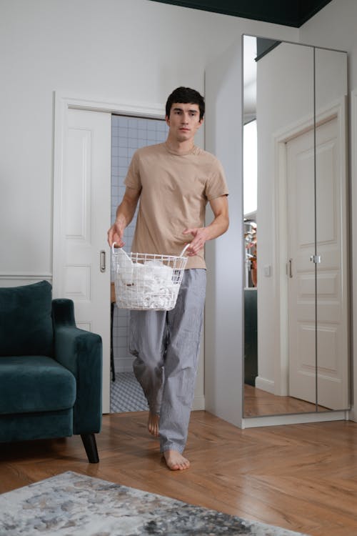 бесплатная Мужчина в серых штанах держит белый полиэтиленовый пакет Стоковое фото