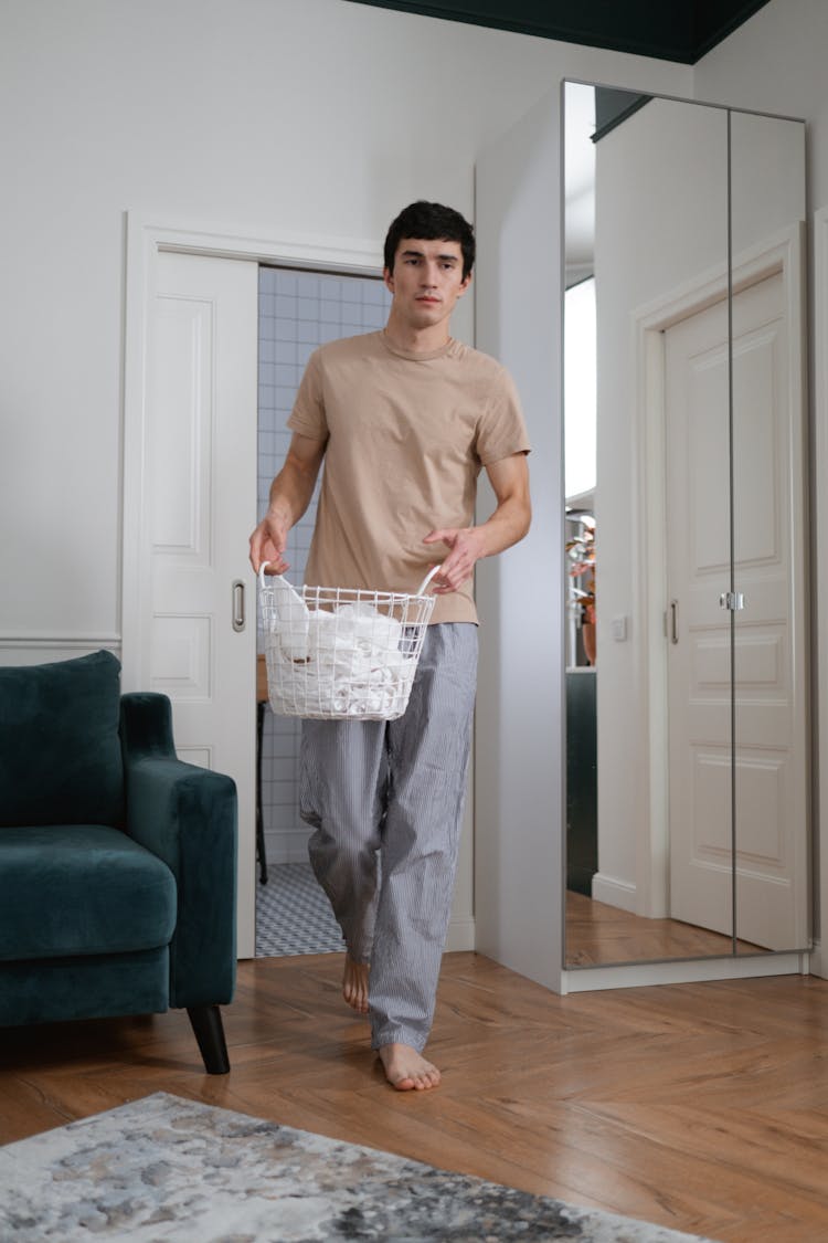 A Man In Beige Shirt Walking Inside The House While Carrying A Basket