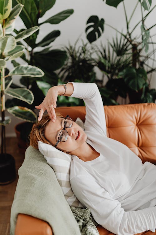 Free Woman in White Long Sleeves Lying on a Couch while in Deep Thoughts Stock Photo