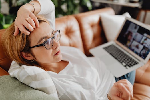 Woman in eyeglasses relaxing on sofa with laptop, enjoying quiet time indoors.