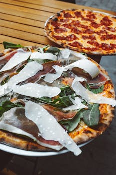 Close-up of two gourmet pizzas, highlighting fresh ingredients in an outdoor setting.