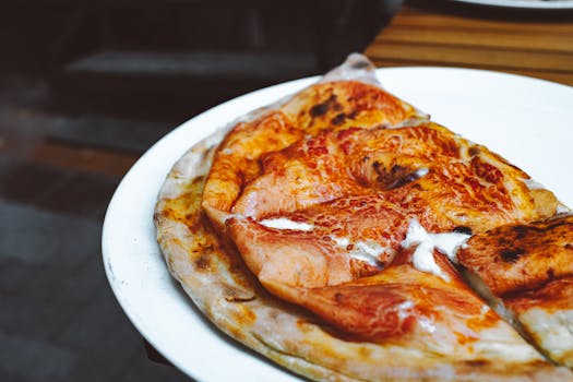 Close-up of a freshly baked pizza on a white plate, showcasing melted cheese in an outdoor setting.