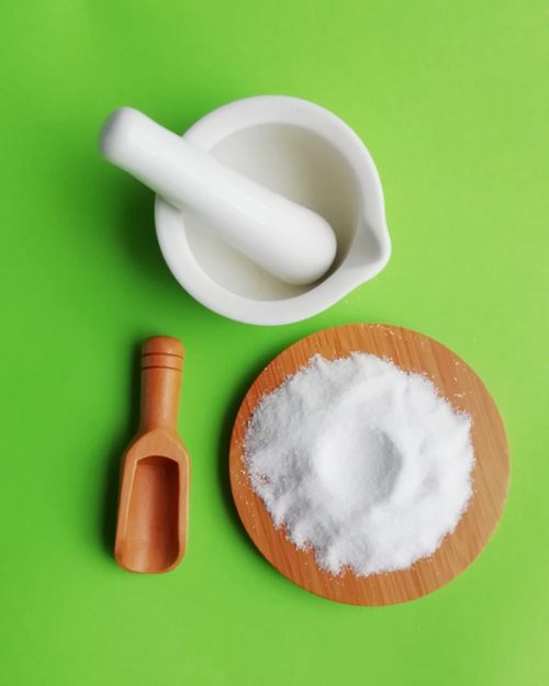 Free White ceramic mortar and pestle with salt on a wooden plate against a vibrant green backdrop, studio shot. Stock Photo