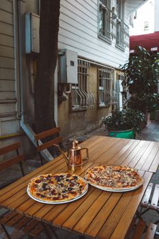 Inviting outdoor pizzeria scene with pizzas on wooden table, perfect for food and lifestyle imagery.