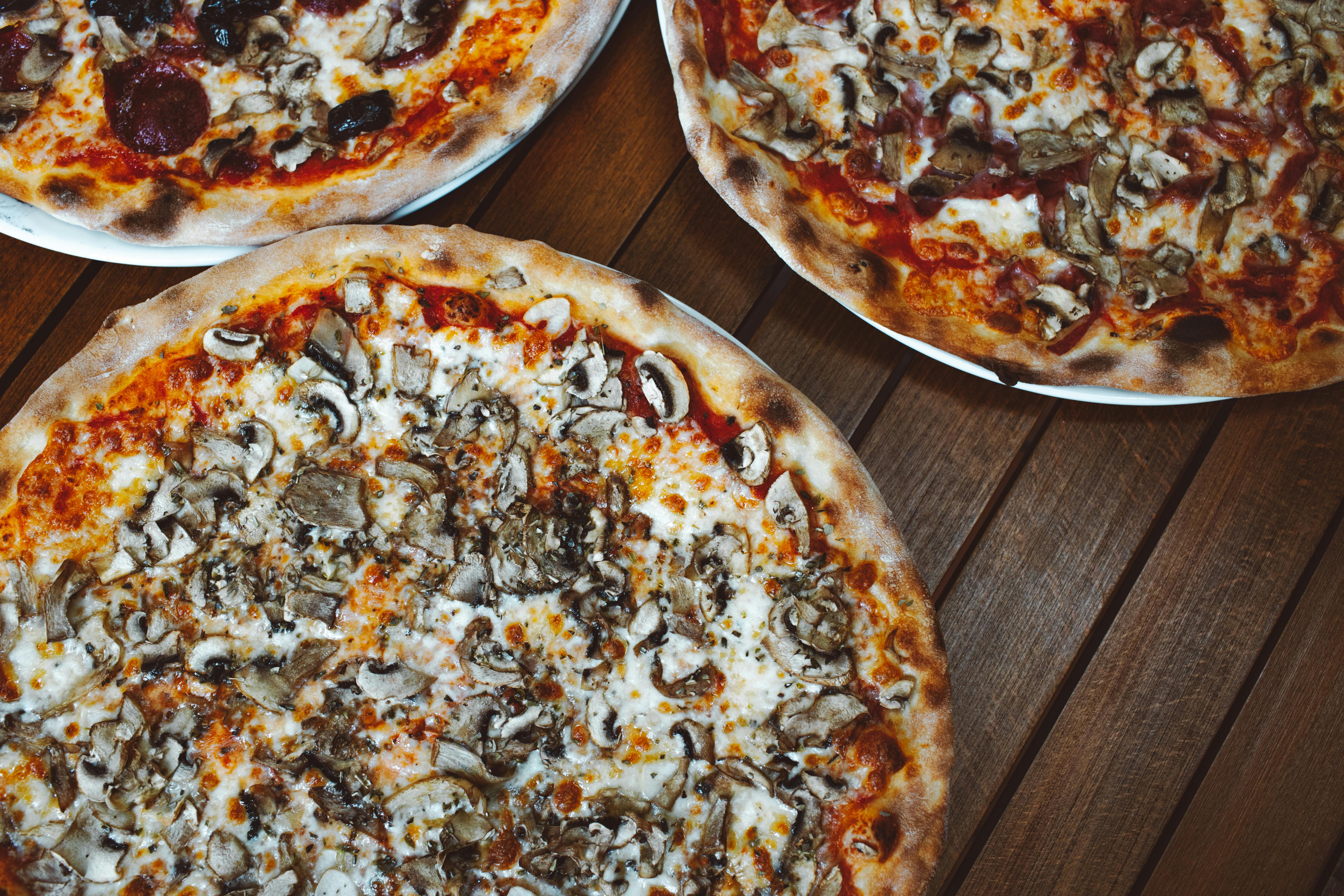Mouth-watering assortment of mushroom and pepperoni pizzas on a wooden table.