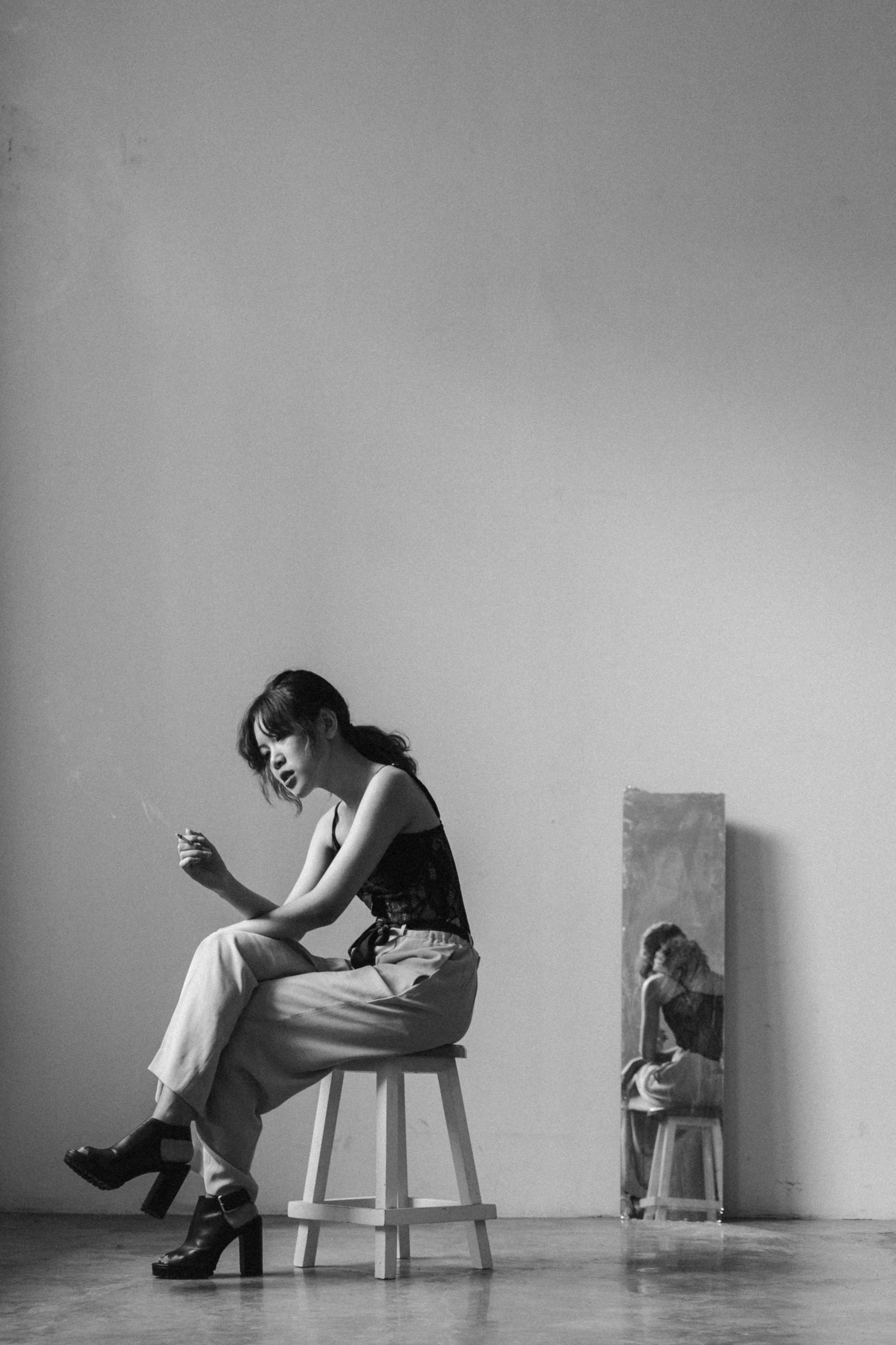 woman sitting on a wooden chair while smoking cigarette