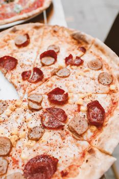 Mouthwatering pepperoni and sausage pizza with visible spices and cheese.