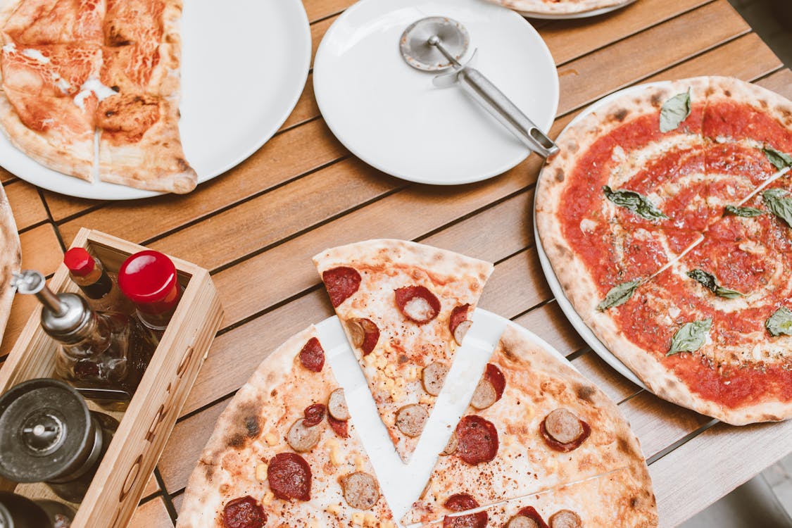 Free High Angle Shot of Pizzas on Wooden Table Stock Photo