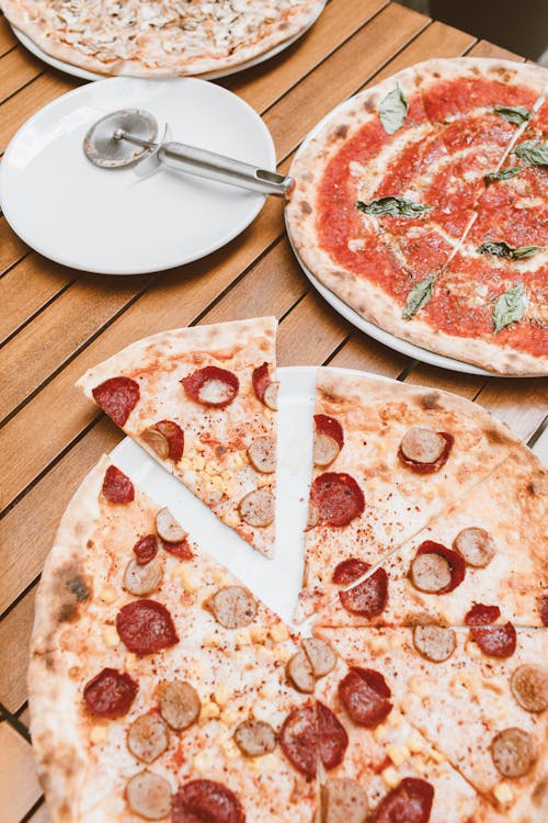 Free Different Flavor of Pizzas on a Wooden Surface Stock Photo