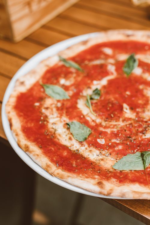 Free Close-up of a delicious margherita pizza topped with fresh basil leaves on a wooden table. Stock Photo