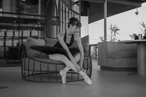 Grayscale Photo of a Ballerina Sitting on the Couch