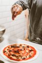 A Hand Sprinkling Cheese on a Pizza Dough with Red Sauce
