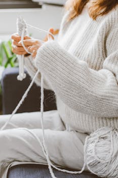 Close-up of a person knitting a sweater with soft yarn, showcasing the art of knitting.
