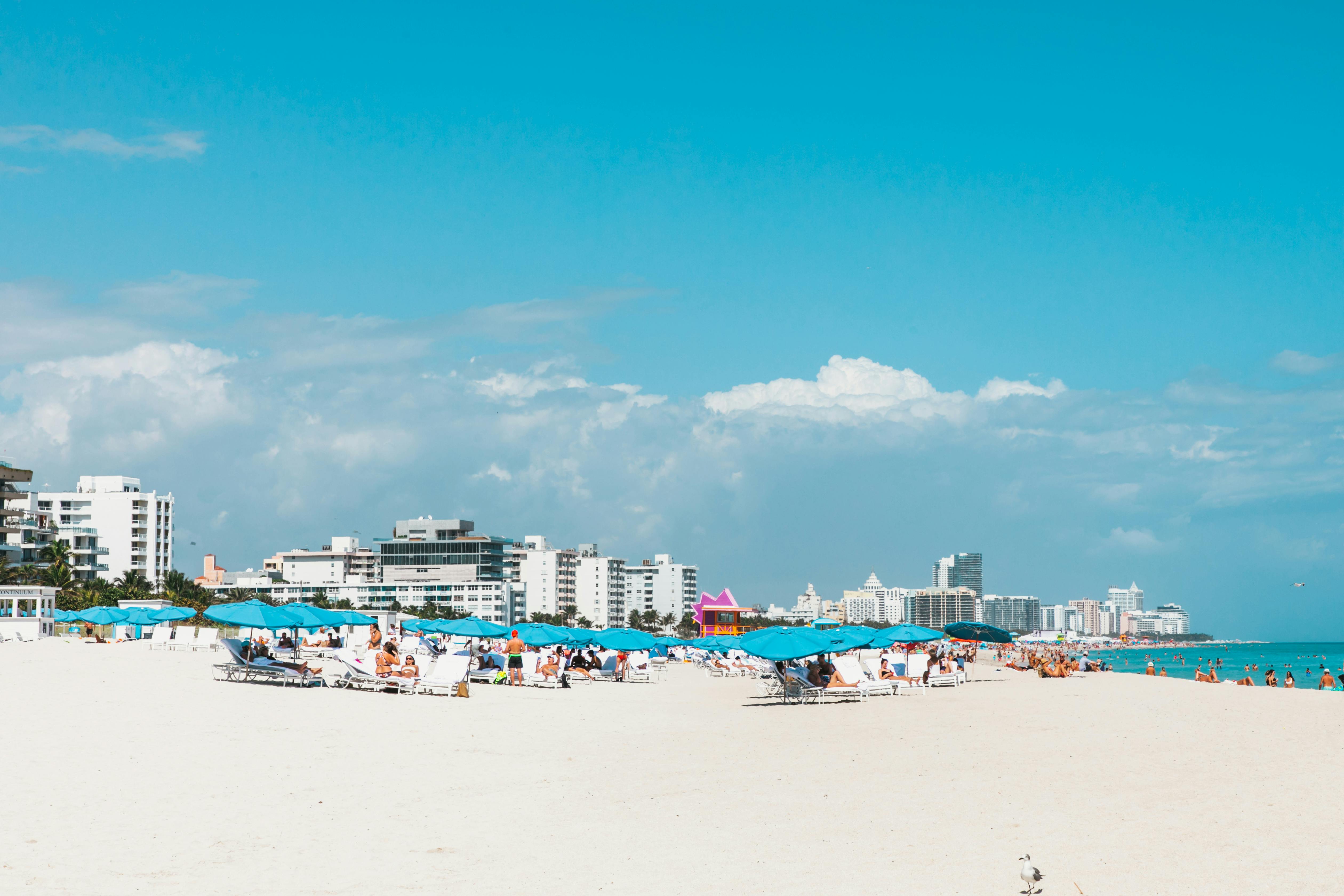 Vibrant Miami Beach scene with blue umbrellas and Florida city skyline under sunny sky