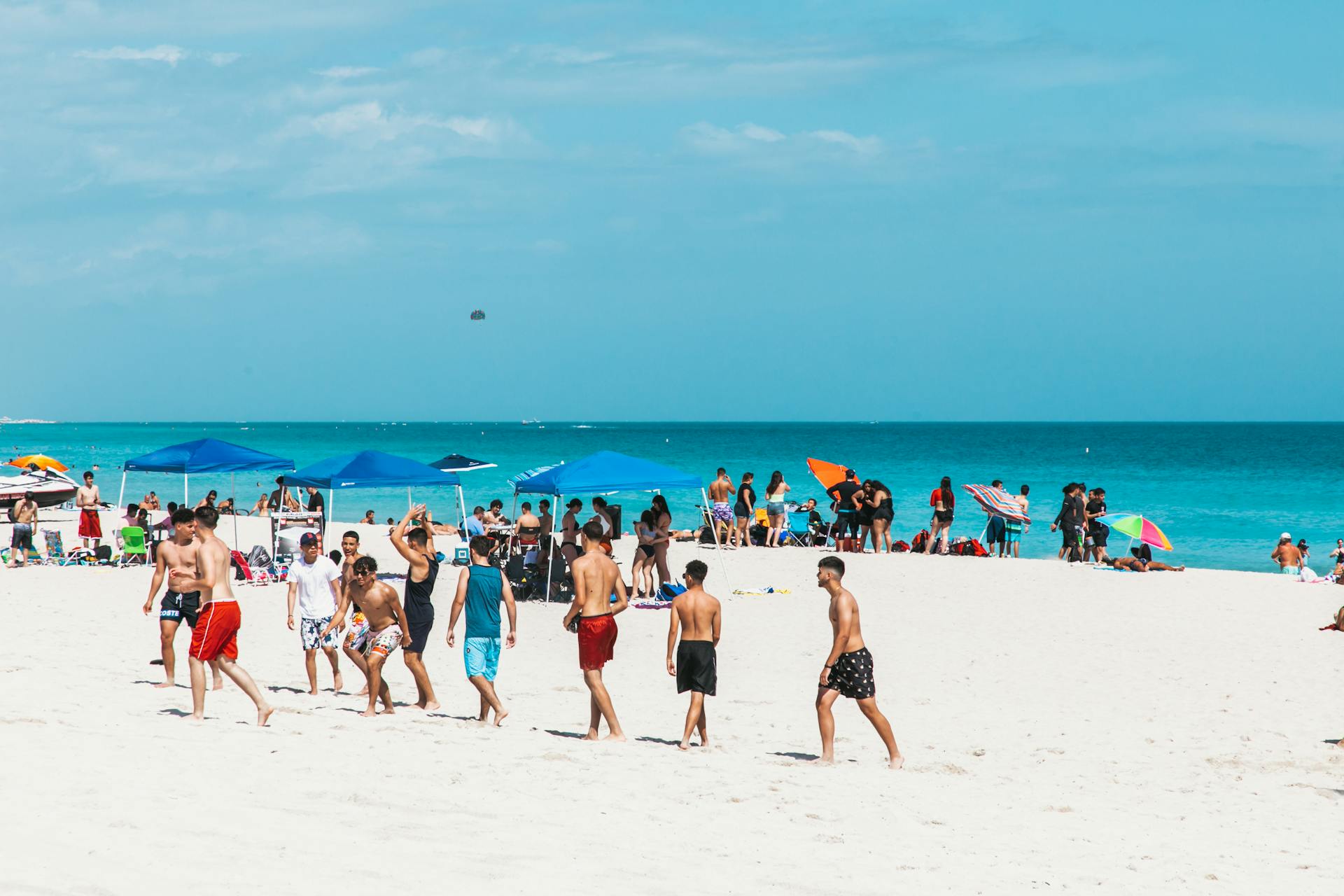 Crowds enjoy a sunny summer day at Miami Beach with clear blue skies and white sand.