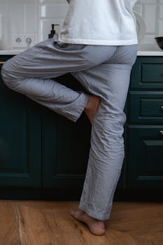 Close-up of a person standing barefoot in pajamas in a modern kitchen.