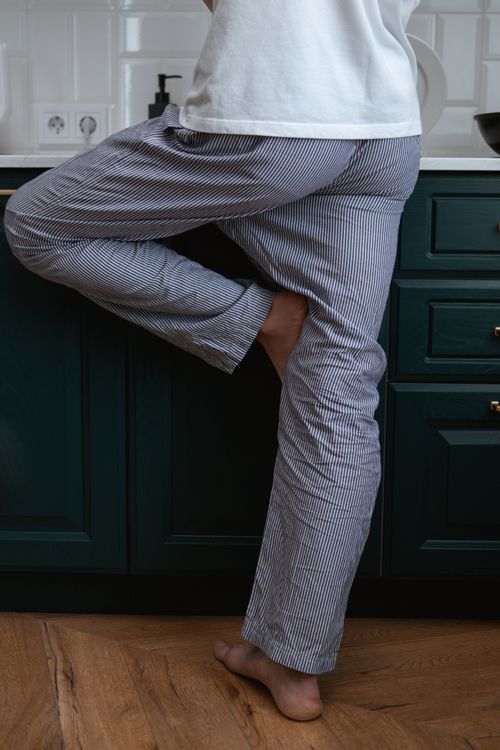 Free Close-up of a person standing barefoot in pajamas in a modern kitchen. Stock Photo