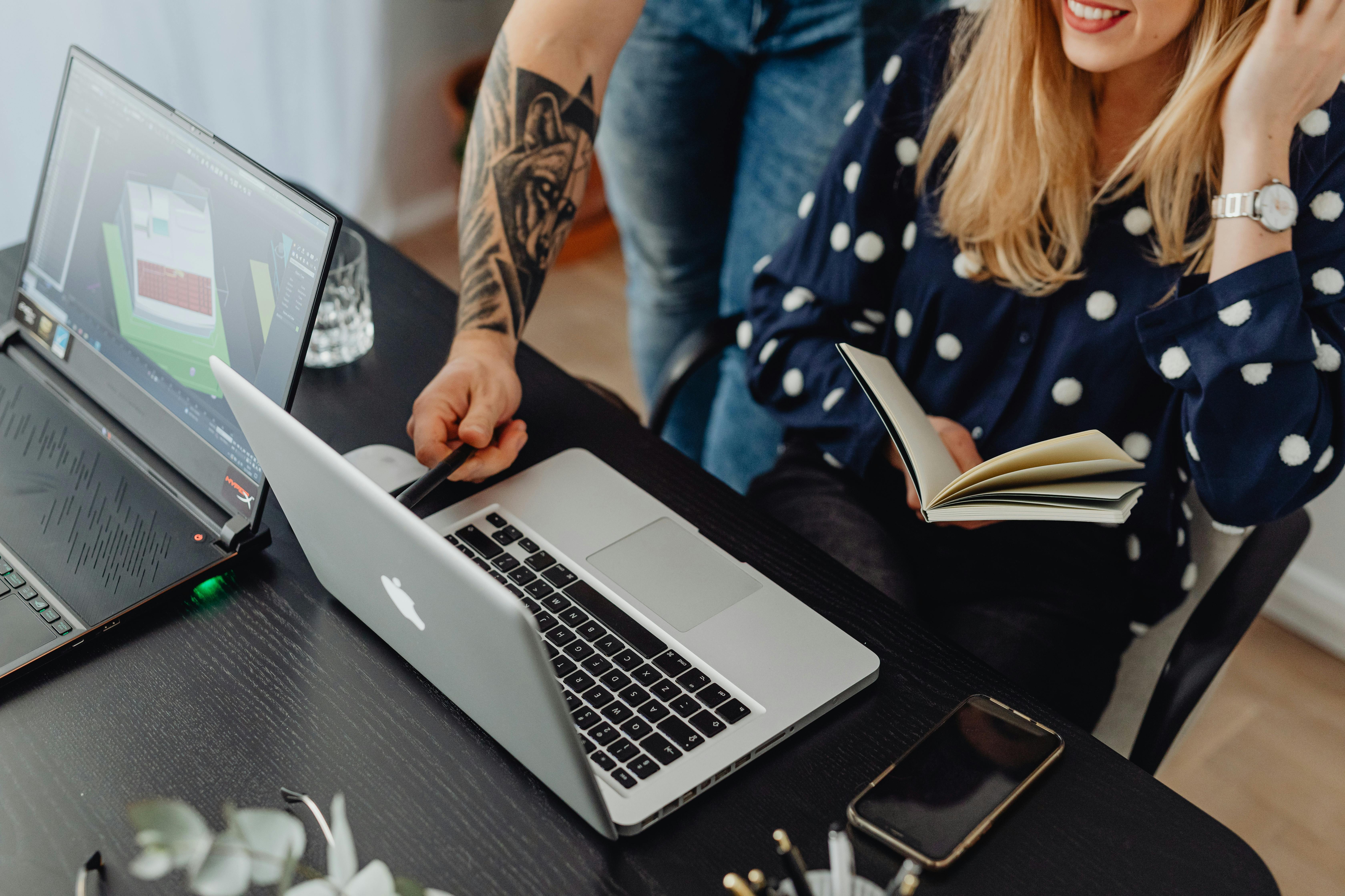 High angle view of a woman and colleague collaborating on laptops in a modern office.
