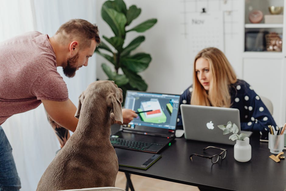 What Pet Food Labels Reveal About Protein Quality Man and woman working at a table with laptops and a dog, fostering teamwork.