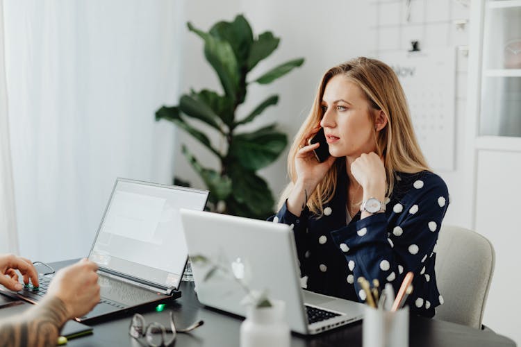 Laptops At Office And Woman Speaking On Phone