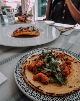 Close-up of delicious tacos served on a decorative plate in a sunny restaurant setting.