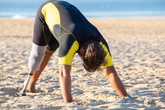 Amputee man in wetsuit doing yoga on a sunny beach showcasing strength and resilience.