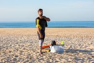 Disabled male surfer with artificial limb looking at camera while wearing diving suit standing on sandy seaside