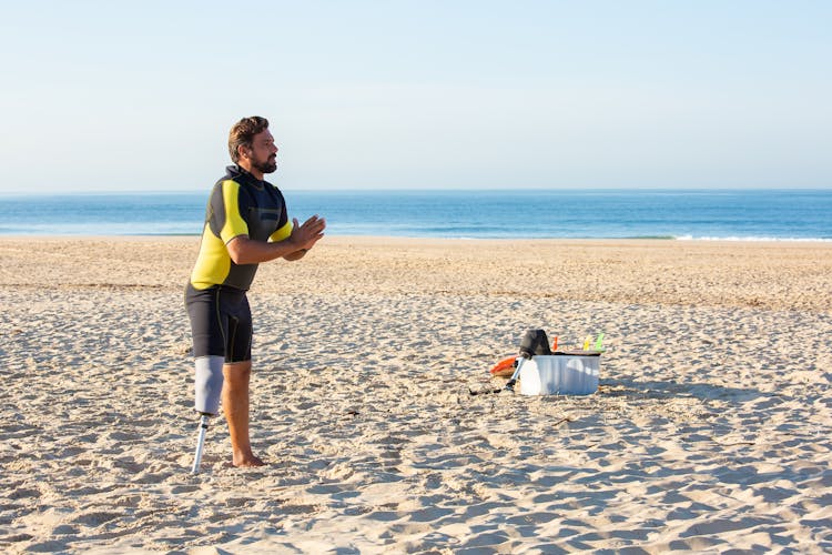 Man With Artificial Limb Warming Up On Sandy Beach