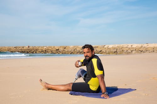 Homme Amputé Surfer Reposant Sur La Plage Avec Boisson En Thermos