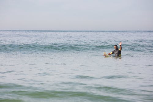 Surfista Masculino Deportivo De Pie En El Agua De Mar Y Agitando La Mano