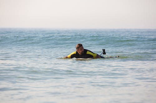 Free Fit male amputee surfer riding surfboard on seawater on belly Stock Photo