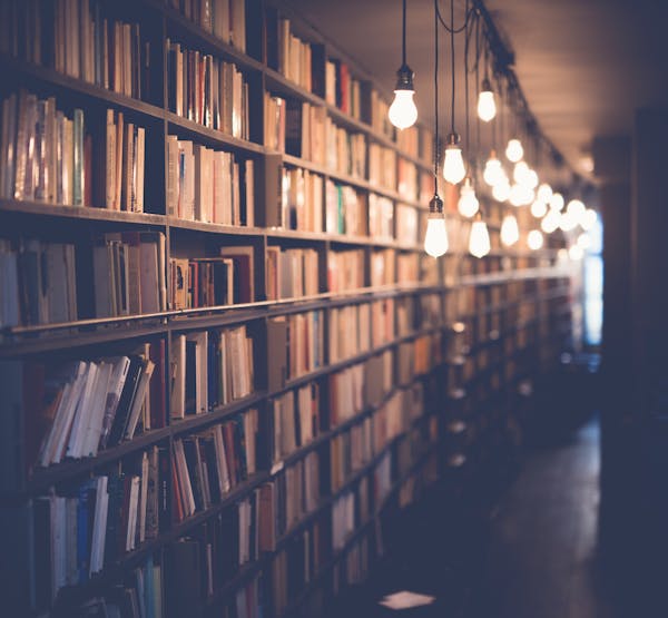 A bright lightbulb above an open book, symbolizing new ideas from reading