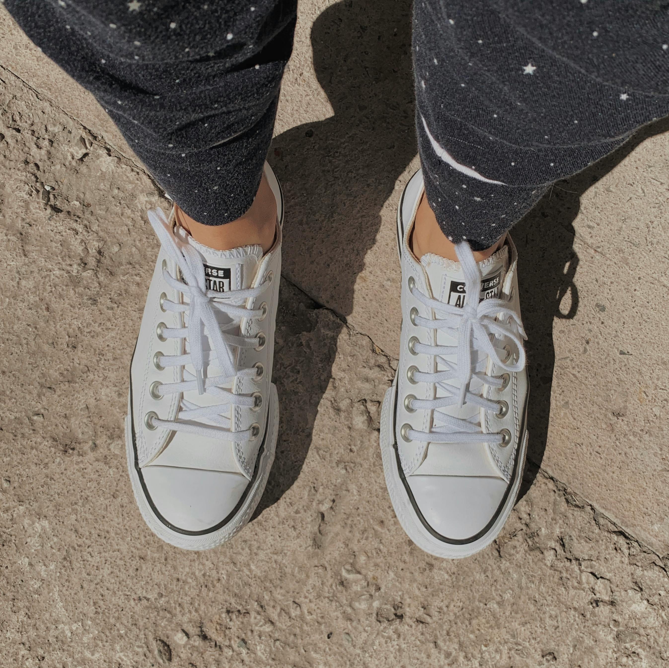 A Person in Black Jeans Wearing White Converse Shoes · Free Stock Photo