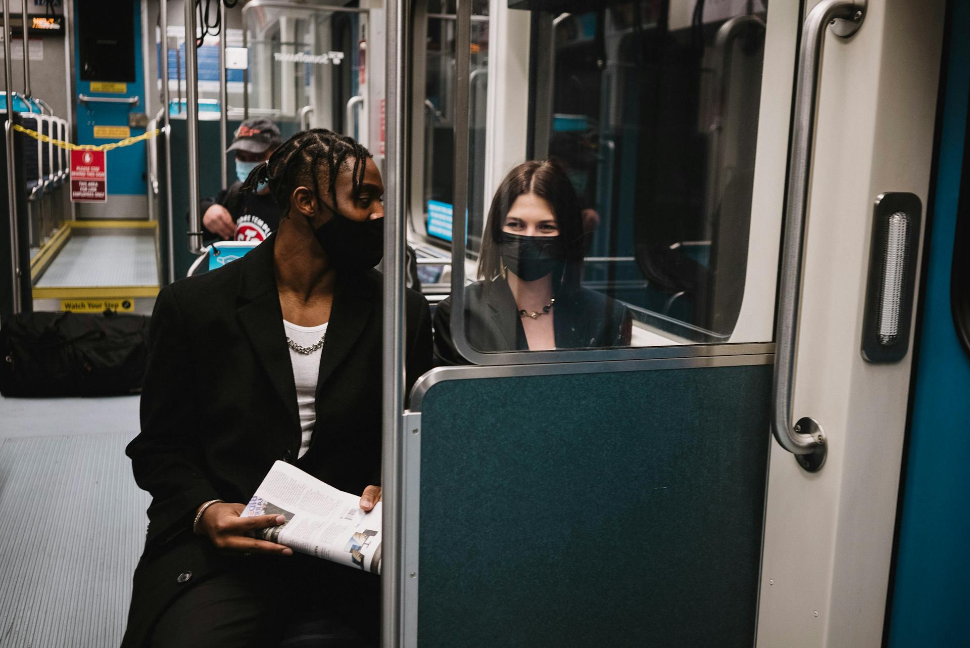 Two masked individuals observed on a train demonstrating new normal travel practices during COVID-19.