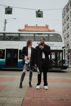 Full length of fashionable young multiethnic couple in trendy outfits chilling on street near bus stop against cloudy sky in Seattle