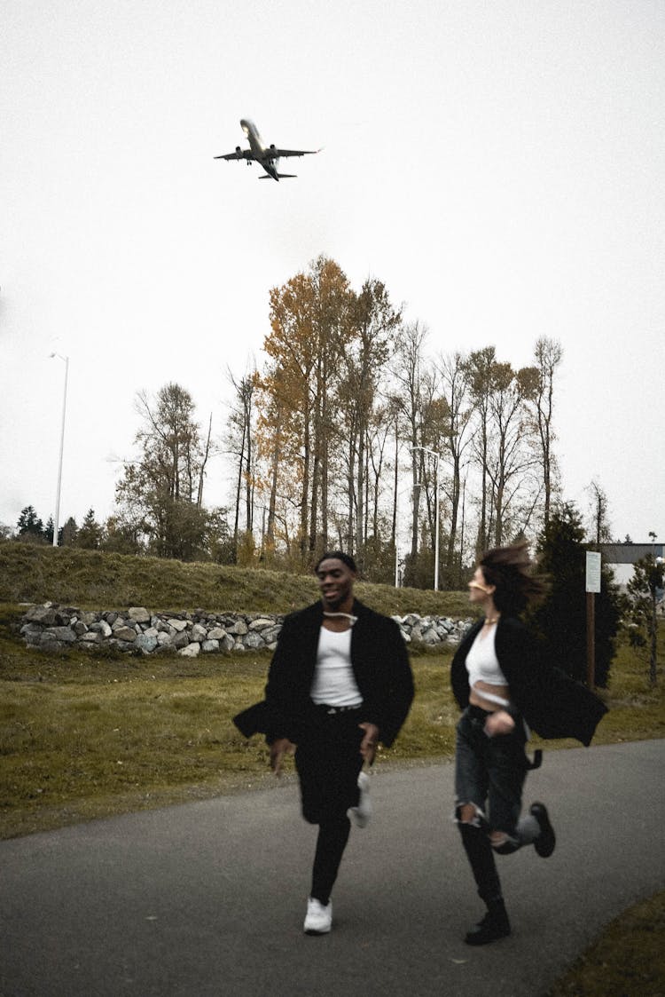 Happy People Running Under Plane Flying In Sky