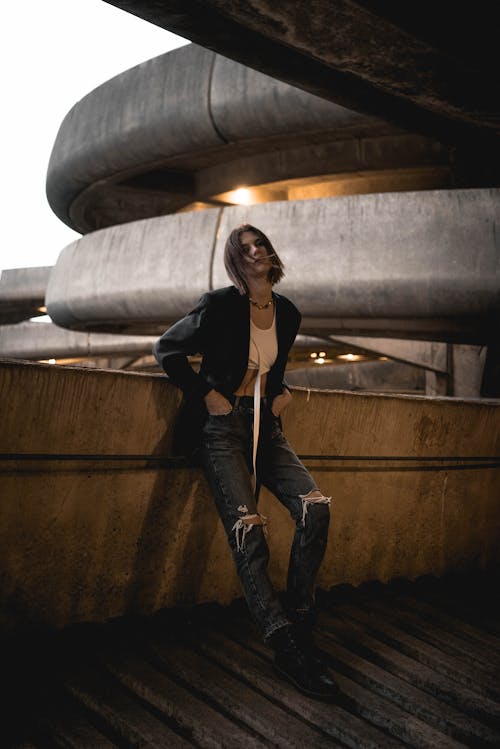 Self assured young female leaning on fence of indoor parking building