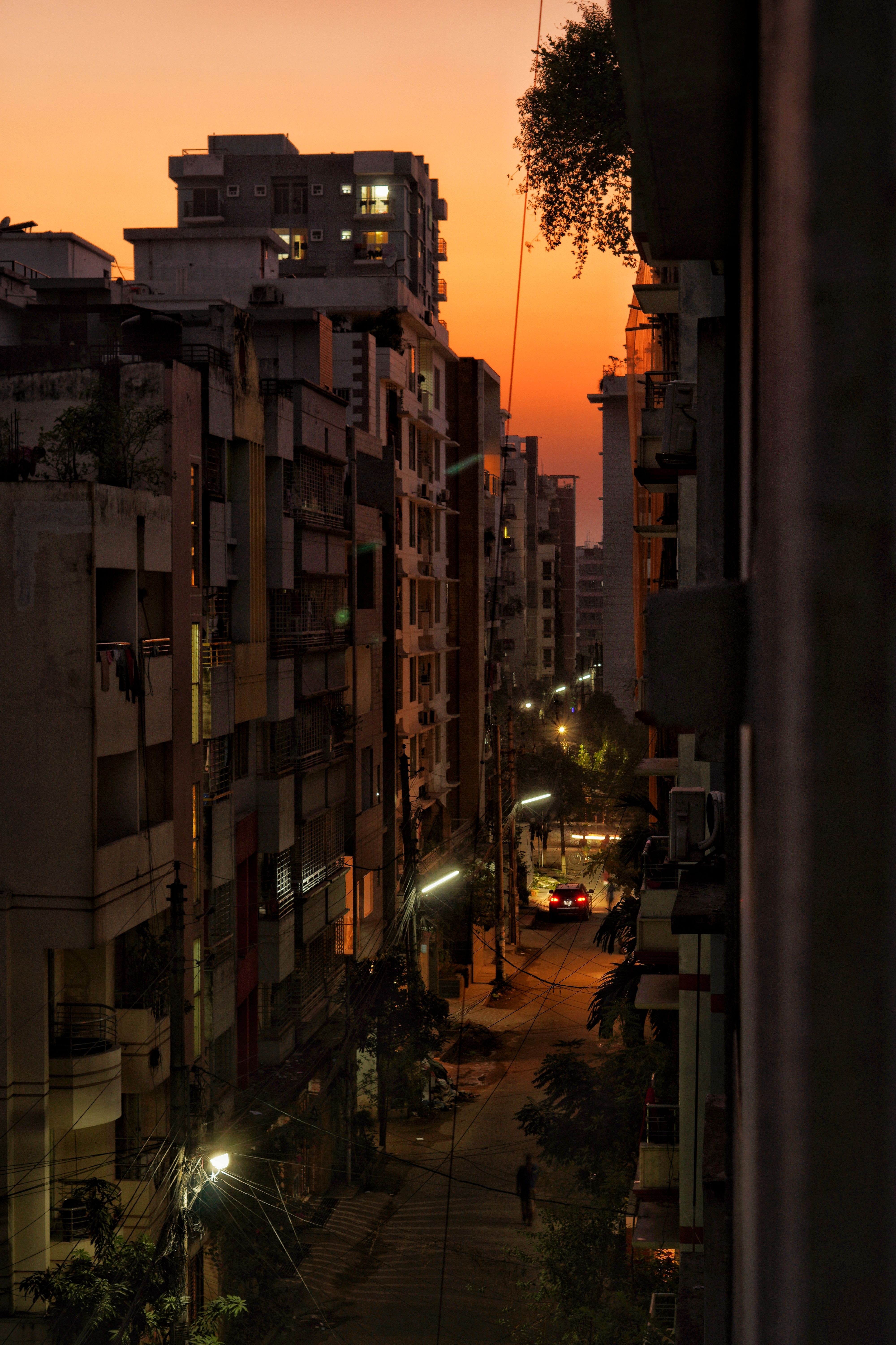 狭窄的城市街道，在橙色日出的天空下，被周围的建筑照亮