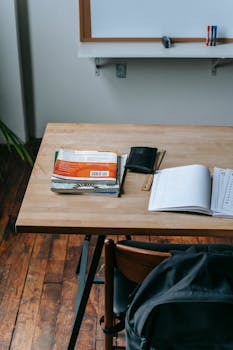 A classroom desk with books, notebook, and whiteboard for a study setting.