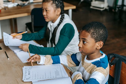 Attentive diverse classmates sitting at desk in classroom