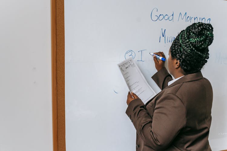 Faceless Black Female Teacher Writing On Whiteboard