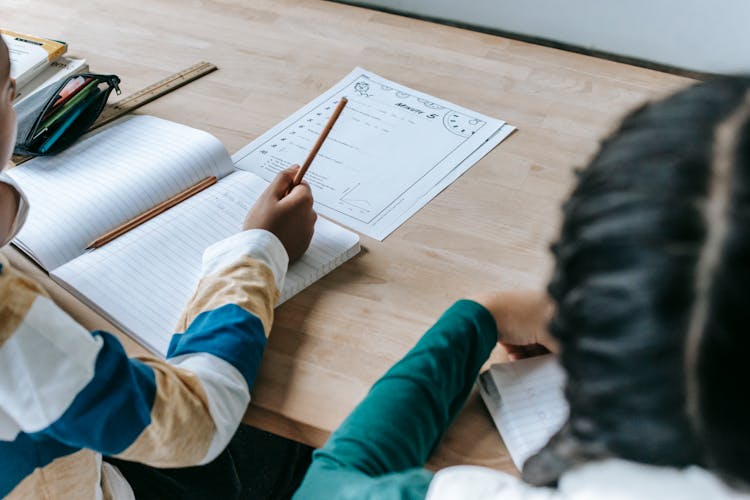 Crop Unrecognizable Diverse Pupils Sitting At Desk In Classroom