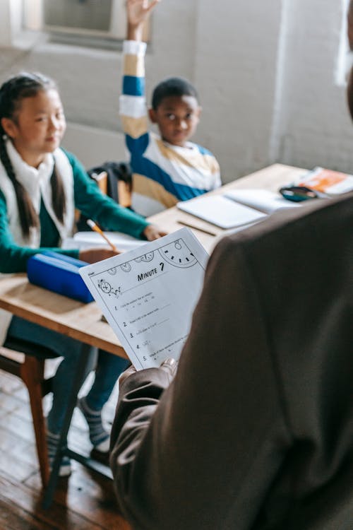 Black schoolboy raising hand in classroom during lesson