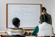 Content black teacher explaining new material to diverse schoolchildren