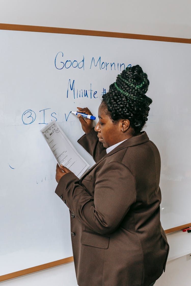 Focused Black Teacher Writing Tasks On Whiteboard