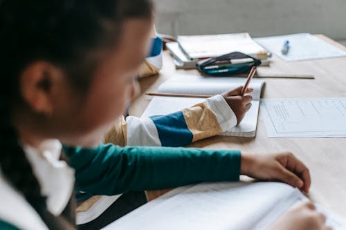 Free Crop schoolchildren sitting at school bench and doing tasks Stock Photo