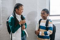 Happy diverse schoolchildren communicating in corridor during break