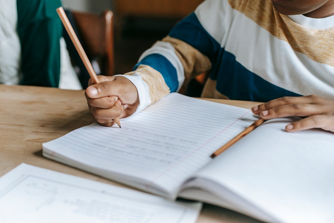 Anonymous black pupil solving task during lesson in classroom