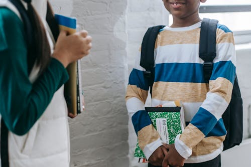 Unrecognizable multiethnic classmates talking in school during break